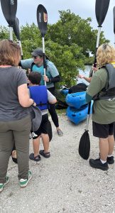 An image of a group of people getting ready to kayak with a kayak leader.