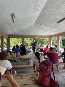 Woman holding up and showing a group of people a marine fossil.