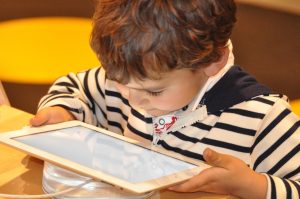 An image of a young child with their face close to a tablet screen.