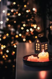 Lit candles and a lit Christmas tree with warm lights