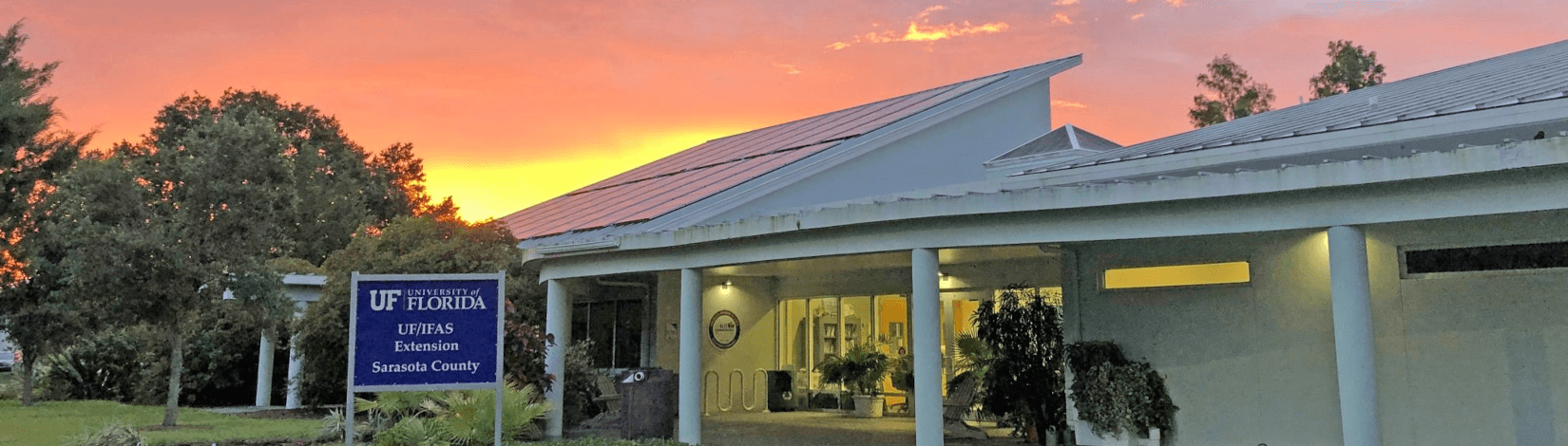 exterior front of uf/ifas extension sarasota county office building, with surrounding landscape, set against a red-orange sky as the sun sets. [credit: uf/ifas extension sarasota county]