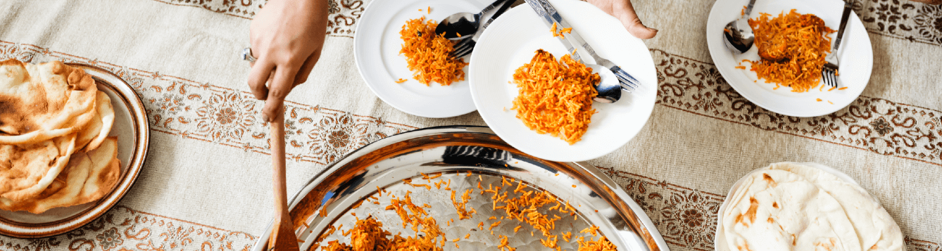 A host scoops out servings of a rice dish and places them on an array of plates. [CREDIT: pxhere.com]
