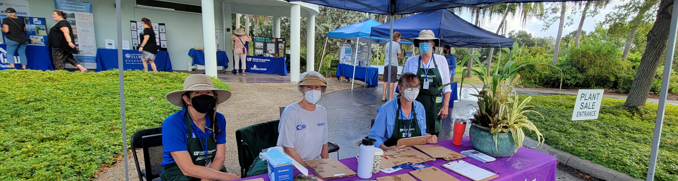 Master Gardener Volunteers staff a check-in table on a rainy Saturday during the group's 2021 plant sale.. [CREDIT: UF/IFAS Extension Sarsaota County]