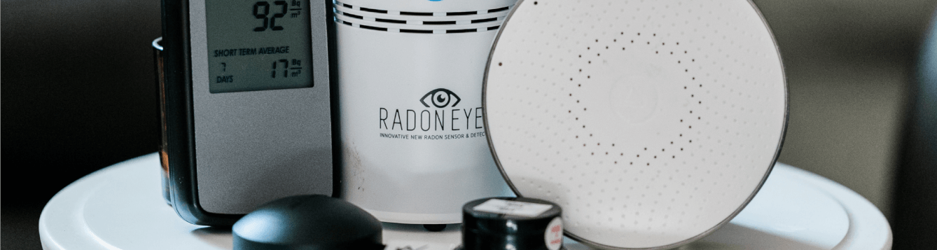 an array of home radon detectors, displayed on a white tabletop. [credit: pixabay.com, take action on radon]