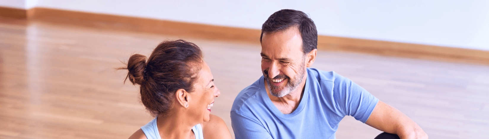 a man and woman share a laugh as they sit on a blue yoga mat. [credit: unsplash.com, kraken images]