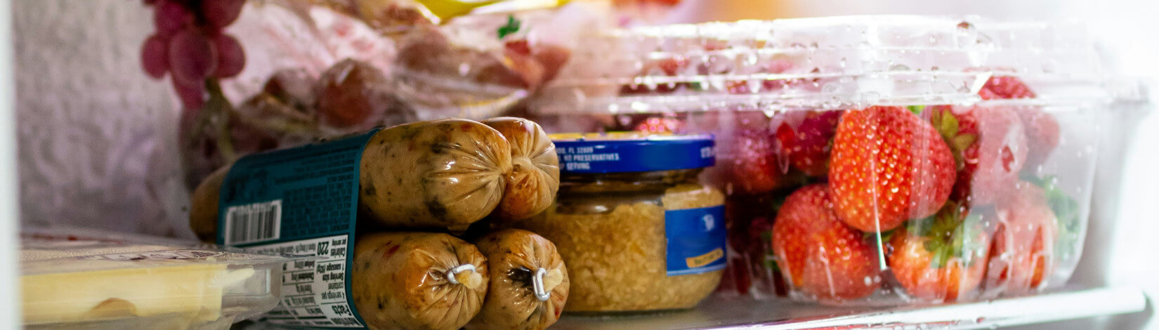 a refrigerator shelf lined with fresh and processed foods. [credit: unsplash.com darrien staton]