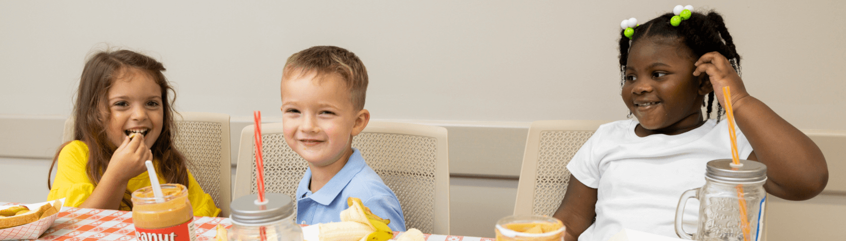 Children smile as they share peanut butter and snacks at a dining table. [CREDIT: UF/IFAS, Tyler Jones]