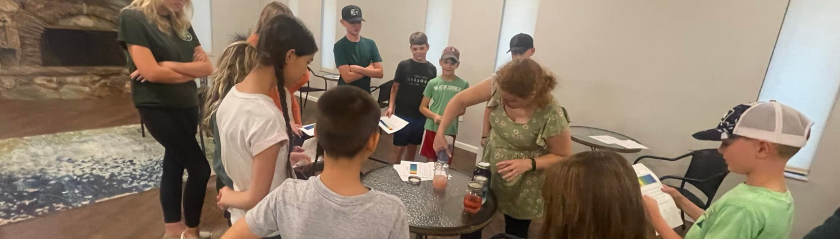 Ashley leads a group of students through a science experiment.