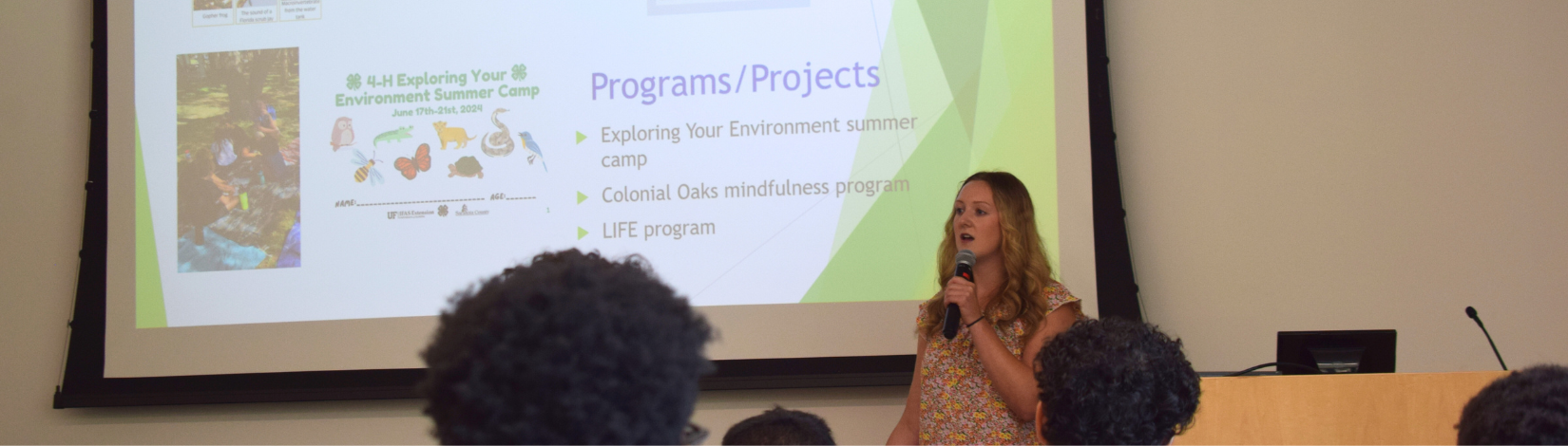 Girl stands in front of a room giving a presentation.