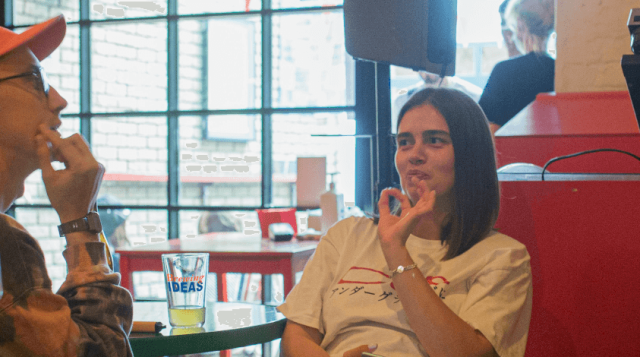 a group of young adults sits at a table in a restaurant/bar, with 