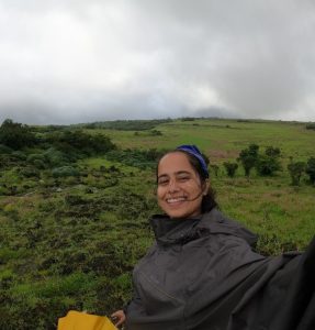 Yukti smiling with a green pasture in the background