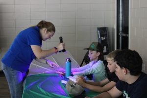 Josey using a UV light to see glo germ on students hands