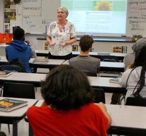 Woman talking to high school students in classroom about sustainability.