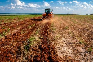 An image of a tractor plowing a field of red, clayey soil. Clay Content is one of the six global soil properties that researchers mapped.