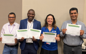 A group of professors holding certificates at a research conference.
