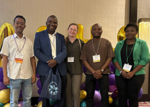 A professor stands with his postdoc and graduate students at the ashs 2025 conference.