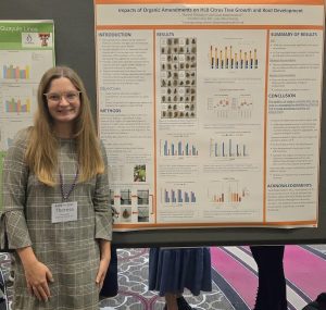 A graduate student stands next to her soil science research poster at the ASHS annual conference.