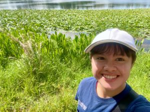 A college student stands at the edge of a wetland area during her summer 2025 experience.