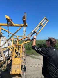 A college student inspecting a tractor during his summer experience at US Sugar.
