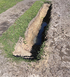 A long trench dug out of the ground for a soil pit to harvest clay.