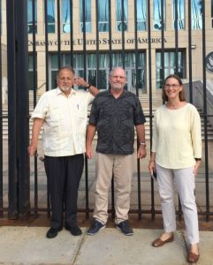 Two men and a woman stand outside the gate of the US Embassy in Havana, Cuba.