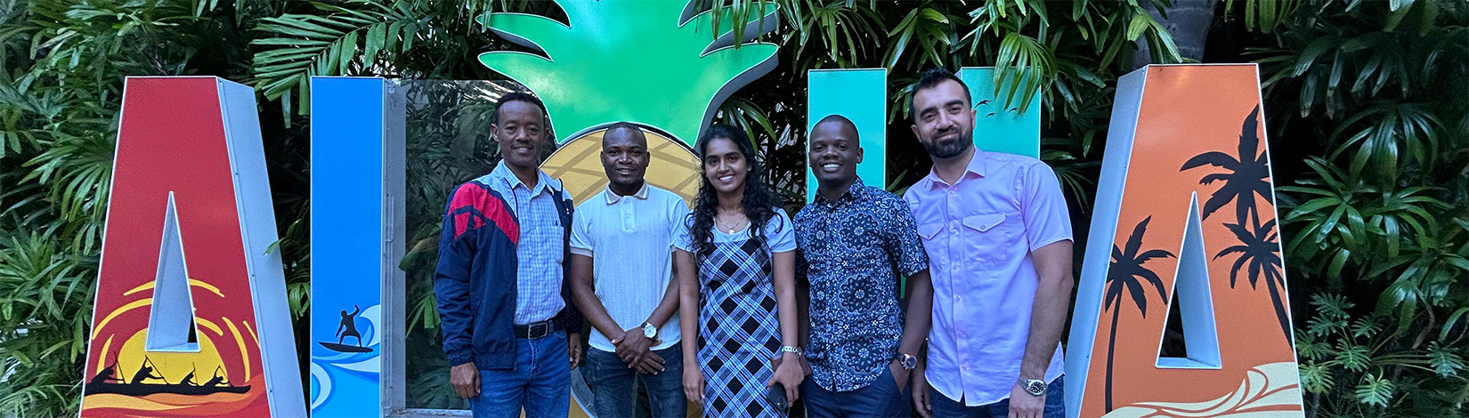 A line of five people standing in front of a large "Aloha" cut out.