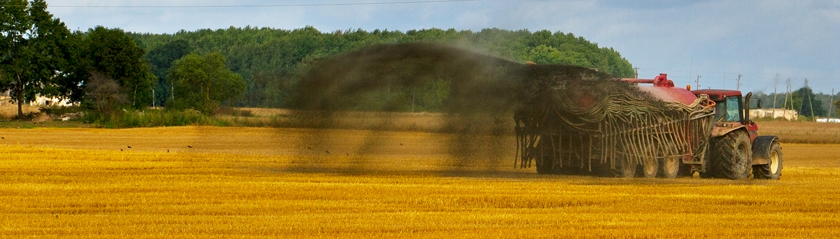 A tractor spreads liquid manure biosolids over a pasture field.