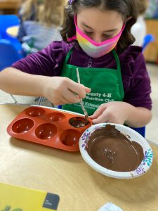 4-H member coating mold with melted chocolate