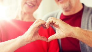 an older couple forming a heart with their hands, to promote american heart month