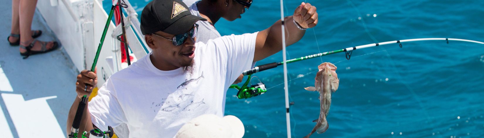 A student catches a fish while fishing on a fishing boat.