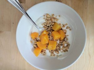 Peaches and yogurt with granola in a bowl
