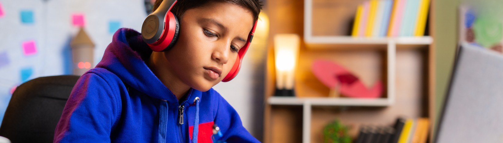 Indian kid making notes from online class on green screen laptop at home - concept of e-learning, intelligence and education.