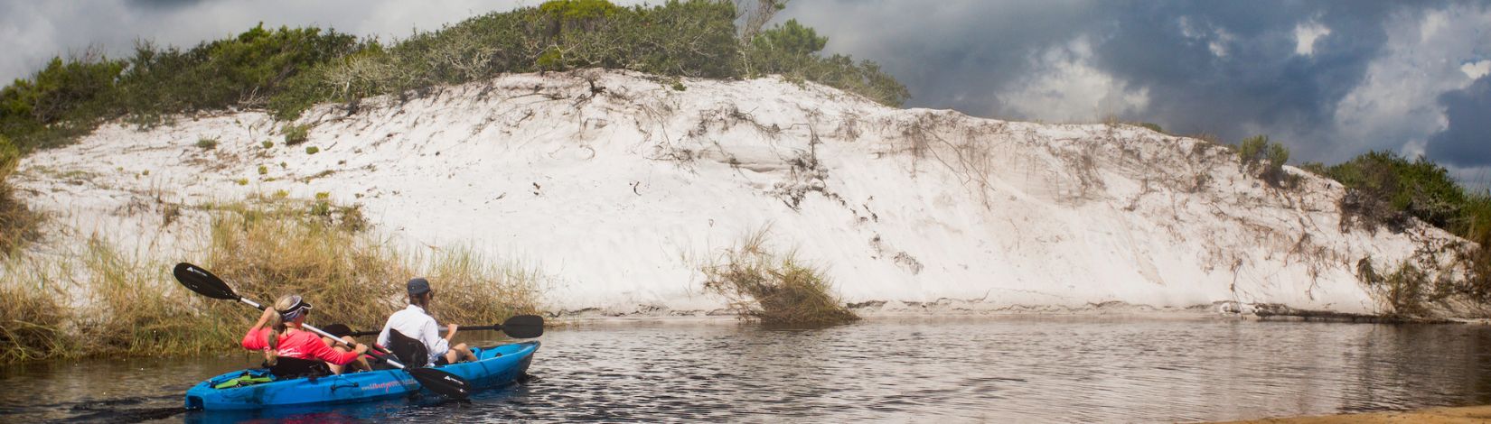 People kayaking at a natural dune lake near Sandestin, Florida.